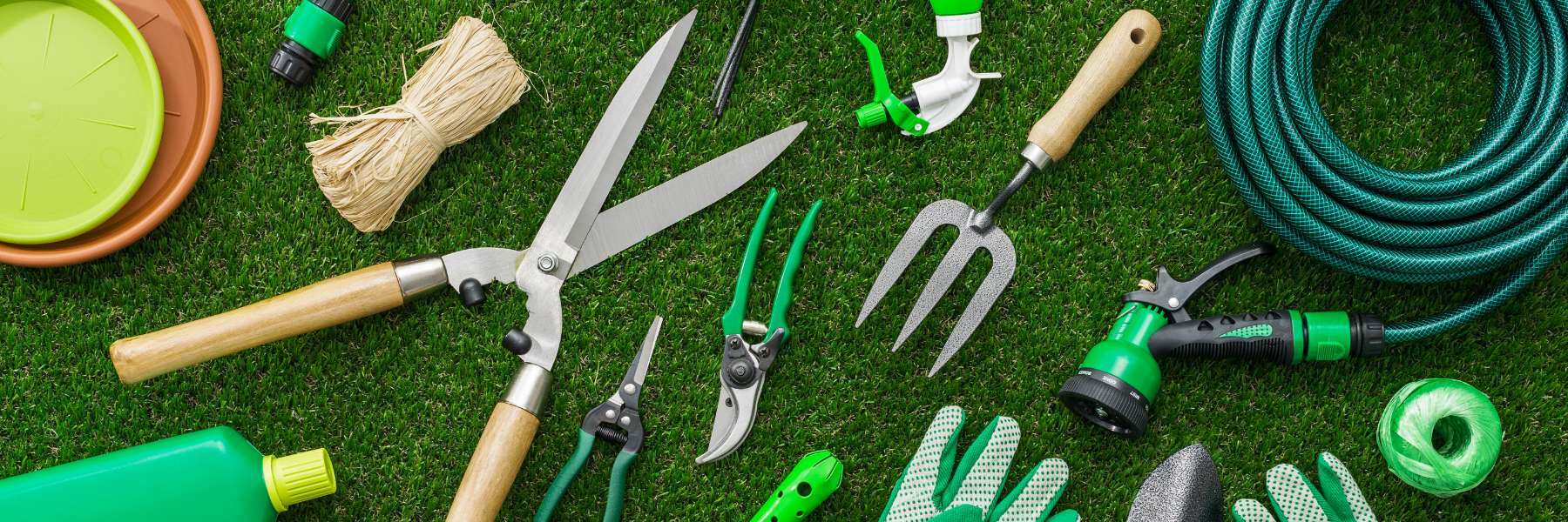 verschiedene Gartenwerkzeuge liegen auf dem Rasen